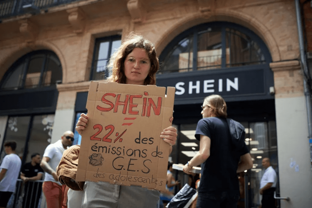A woman wearing a Shein dress and protesting against fast fashion practices